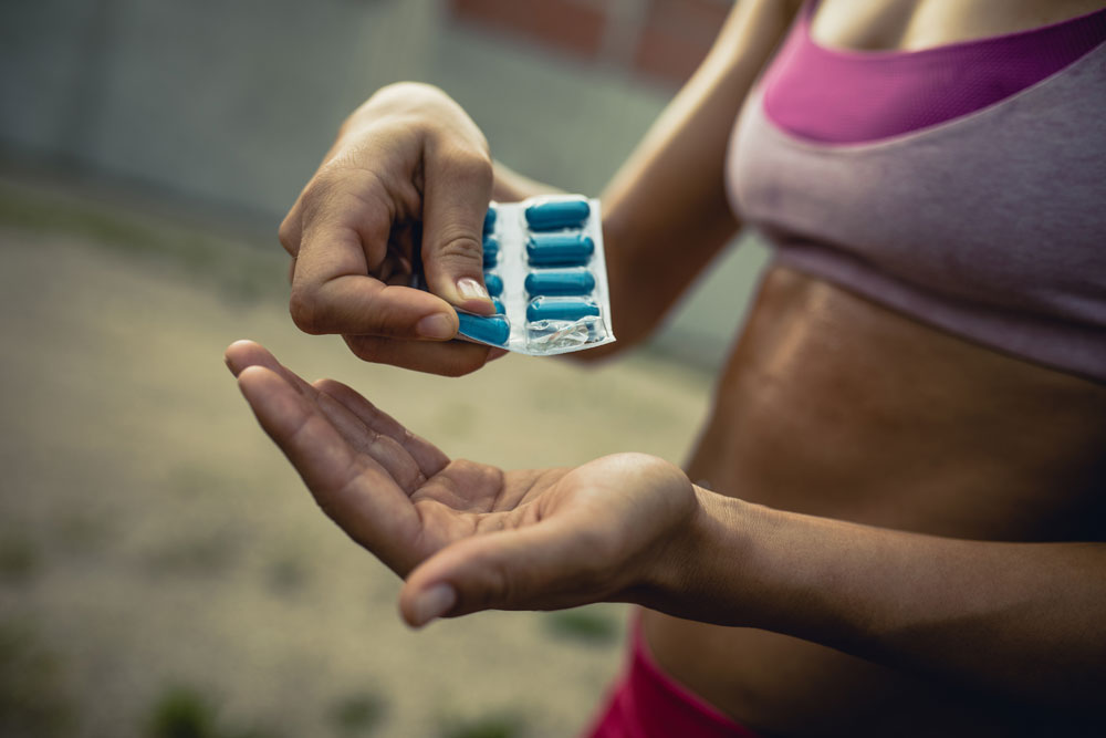 En kvinna i träningskläder håller i piller